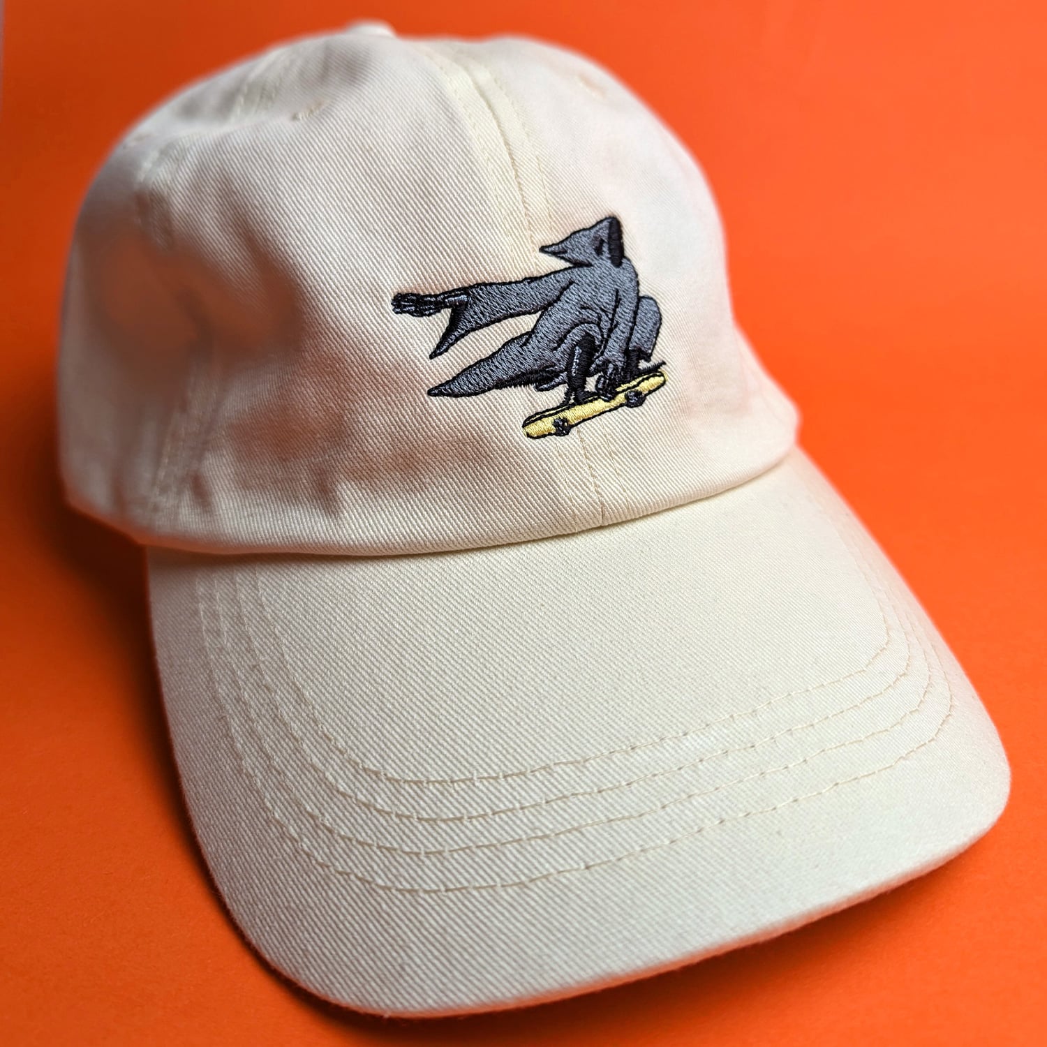 Beige cap with Grim Reaper embroidery on orange background - front view