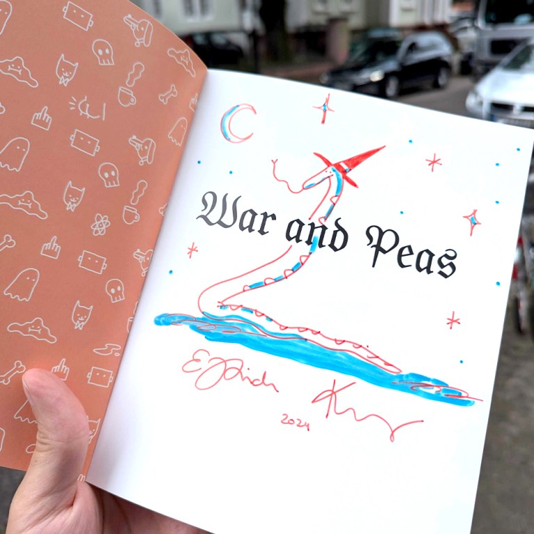 Photo of a signed first page of the book 'Funny Comics for Dirty Lovers' by War and Peas. The page features an original drawing of a snake wearing a witch hat along with the title 'War and Peas' and signatures by the artists. The background shows whimsical patterns with various doodles including ghosts, cats, and bones, creating a playful aesthetic.