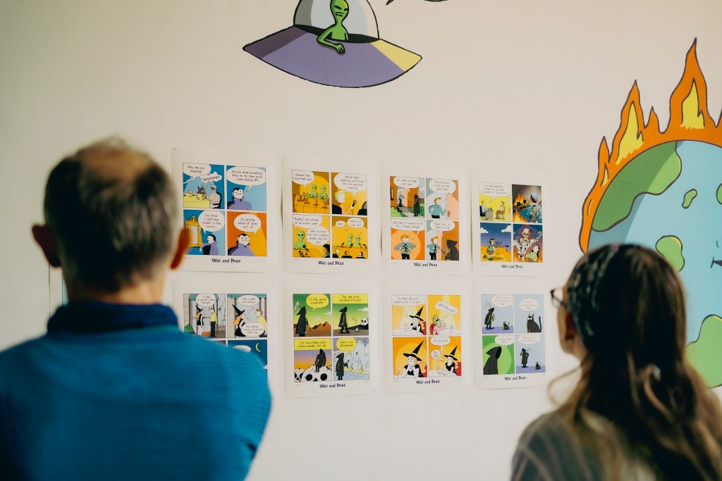 People looking at comic exhibition by webcomic duo War and Peas. Photo: Tina Stariha / Kino Šiška
